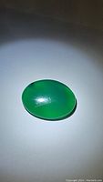 Oval vivid green natural onyx gemstone with cabochon polish, illuminated to show color and texture.