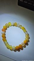 Yellow agate bracelet on white background, showing circular arrangement of multi-tonal yellow and cream beads, each about 8mm diameter, glossy finish.