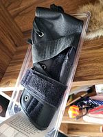 Black ankle brace with adjustable Velcro straps on a wooden surface.