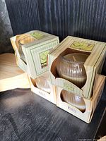 Four brand new cucumber melon scented candles in original packaging stacked on a shelf.