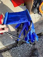 Side view showing blue fabric seat and black metal frame, partially folded.