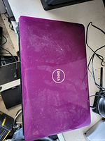 Closed view of purple Dell laptop lid with Dell logo, showing dusty and smudged surface.