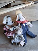 Three fabric dog dolls posed together showing details of clothing and design.