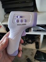 Close-up of handheld infrared forehead thermometer showing side controls and ergonomic grip.
