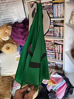 Green umbrella hanging, showing part of the green fabric with black stripes and the handle at the bottom.