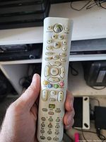 Hand-held white Xbox 360 remote control showing front face with all buttons and Xbox logo at top center.