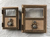 Photo showing two vintage post office box fronts with locks, one larger and one smaller, side by side on a white surface.