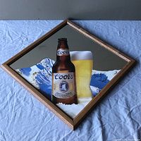 Front view of the diamond shaped Coors beer sign showing bottle, glass, and mountain background.