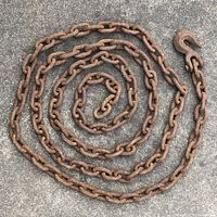 Coiled heavy duty metal chain with attached hook, showing rust and corrosion on all pieces.