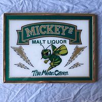 Full view of the framed Mickeys Malt Liquor The Mean Green wall sign on a fabric background.