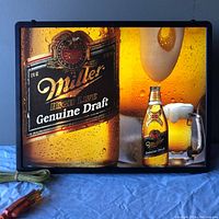 Full view of the lighted Miller Genuine Draft beer sign hanging on a wall with cord and plug visible.