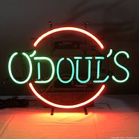 Front view of neon sign lit up showing green lettering "O'Doul's" with red circle.