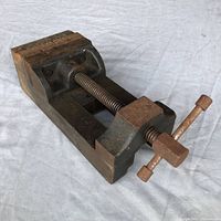 Side angle showing full vise body, screw, and turn handle with aged corrosion.