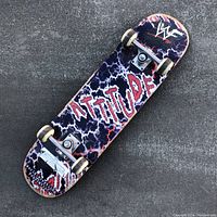 Underside of the skateboard showing WWF logo, 'ATTITUDE' bold graphics, lightning pattern, and wear on the deck.