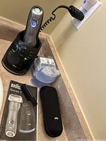 Braun Series 7 electric shaver in charging and cleaning station with travel case, cleaning brush, and cleaning fluid cartridges on countertop.