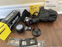 Full lot showing Nikon Coolpix 4500 camera accessories including charger, battery, wide lens, slide copier adapter with box, manuals, and camera case.