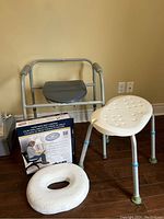 Full lot photo showing the elevated toilet seat with metal arms, shower seat, and donut cushion with box