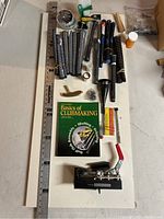 Top-down view of all items in lot including measuring ruler, grips, tools, putter head, and book.