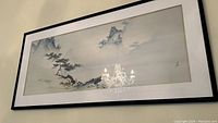 Framed Japanese art print hanging on wall with visible reflections.