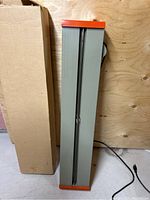 Full view of the heating rod bender showing grey metal housing with orange end caps and attached power cord