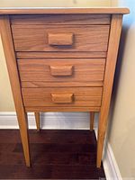 Front view of a wooden cabinet with three drawers and rectangular wooden handles.