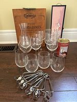 Photo showing all items in the lot: wooden wine box, Riedel decanter, stemless and stemmed wine glasses, wine taster glass, and metal escargot tongs.