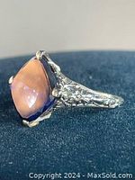 Side view showing ornate floral filigree band and prong setting