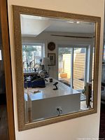 Front view of a large rectangular mirror showing the reflective surface and detailed gold decorative frame.
