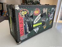 Photo of green vintage travel trunk showing various music-related stickers and worn corners