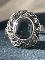 Front view showcasing the central oval black onyx stone surrounded by marcasite accent stones in silver filigree setting.