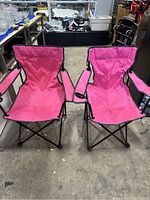 Front view of two pink foldable camping chairs side by side, showing their fabric seats and black metal frames.