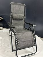 Front side view of the black adjustable patio lounge chair showing full length and mesh seat with attached pillow.