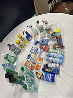 Top-down view of the entire cleaning product lot spread on a white round table, showing the assortment of sprays, bottles, and wipes.