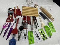 Photo showing the full kitchen utensil set including rolling pins, cutting board, spatulas, scissors, knives, graters, peelers, and other tools.