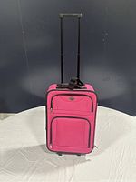 Full front view of pink Jet Stream softside luggage with black telescoping handle fully extended and two front zippered pockets.