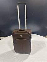 Brown Tucci Italy suitcase standing upright showing telescoping handle extended and front panel detail.
