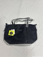 Front view of new black Roots 73 tote bag with straps covered in plastic, original tag attached.