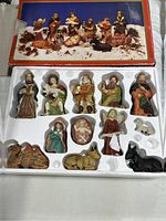 Photo of 12 porcelain nativity figurines in custom styrofoam tray with box lid showing scene image above.