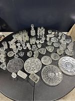 Top view of the entire crystal dinnerware set on a black table showing various plates, glasses, decanters, and serving dishes.