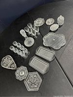 Photo showing entire 26-piece vintage crystal set with decanter, glasses, trays, ashtrays, and bowls arranged on black surface.