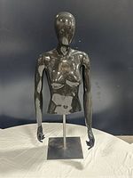 Front view of the glossy black female half body mannequin mounted on a metal stand.