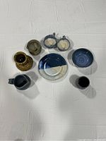 Overview of all 7 ceramic pottery pieces arranged on white fabric.