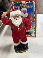 Front view of the singing and dancing Santa Claus figurine, showing Santa in red suit with fur trims and base distinctively marked 'merry Christmas'.