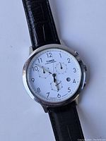 Close-up of round white dial showing Timex branding, chronograph subdials, date window, and black Arabic numerals.