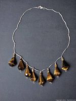 Full view of the vintage sterling silver necklace with seven faceted tiger eye pendants evenly spaced along the chain.