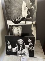 Three black and white photographic prints on cardboard. One shows a man reading newspaper, one shows a person speaking into microphone, and one shows a close-up side profile of person viewing artwork.