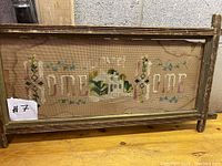 Full view of embroidered "Home Sweet Home" sampler in rustic wooden frame with glass.