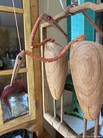 Photo showing close-up of two hand carved wooden crane puppets suspended and attached to a wooden frame, highlighting the segmented movable neck with wood beads and the shape of the wooden bodies.