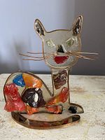 Full front and side view of the MCM lucite cat sculpture with copper foil inclusions on a white surface.