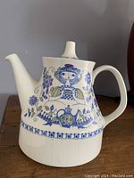 Full side view of the ceramic tea pot showing stylized female figure and floral blue decoration